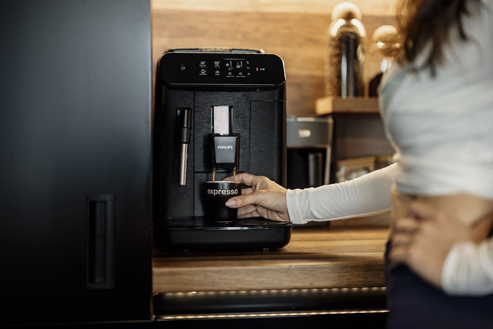 Persona usando una cafetera superautomática en la cocina